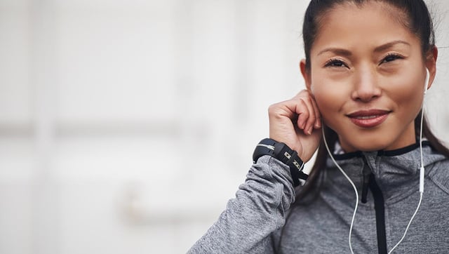 woman putting in her ear buds while go on a run and using the abim audio review 