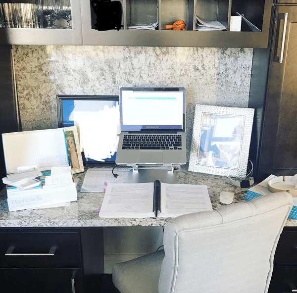 a desk with a laptop, flashcards and books 