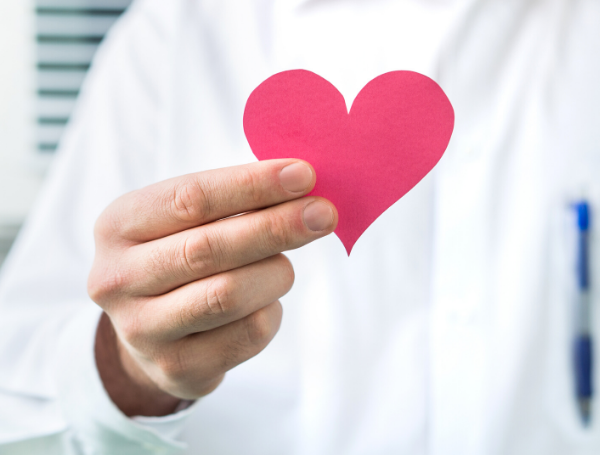 physician in white coat holding up a red paper heart, physician burnout prevention 